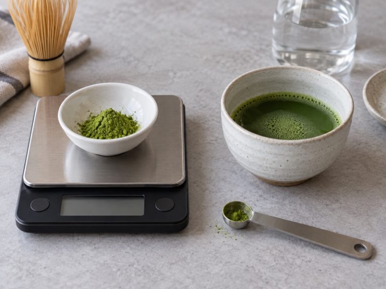 Pure matcha powder on a scale beside an unsweetened cup of matcha
