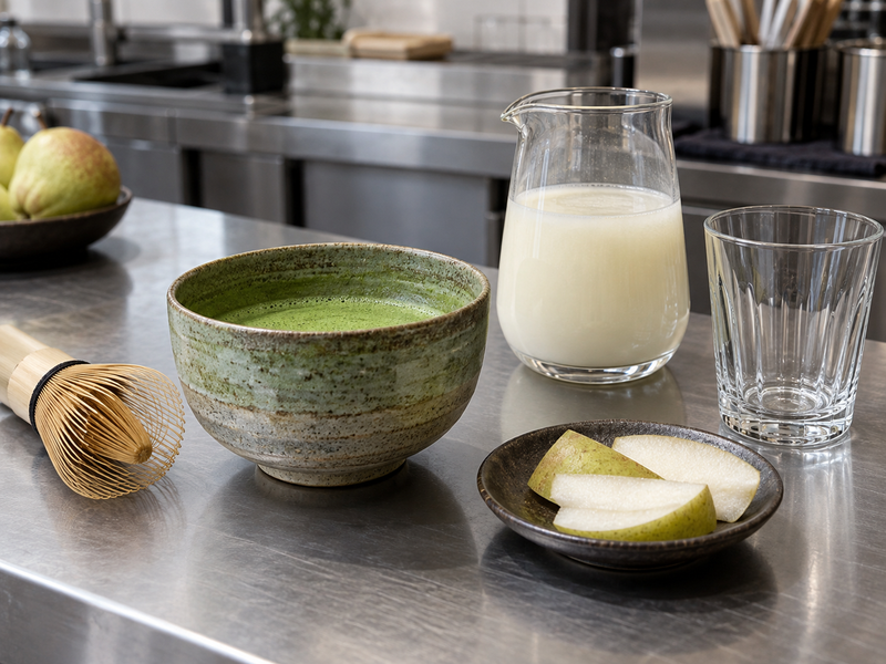 Whisked matcha beside a smooth pear milk base