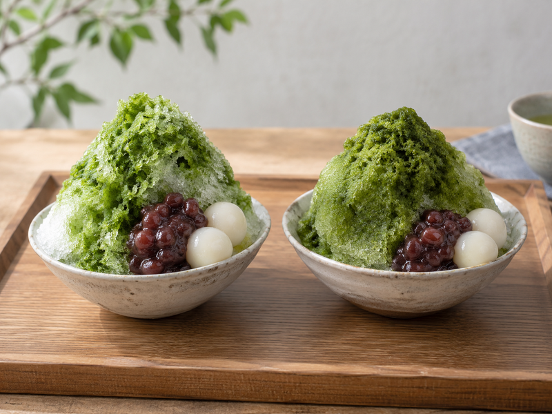 Matcha kakigori assembly with azuki, shiratama and condensed milk placed beside a shaved ice mound