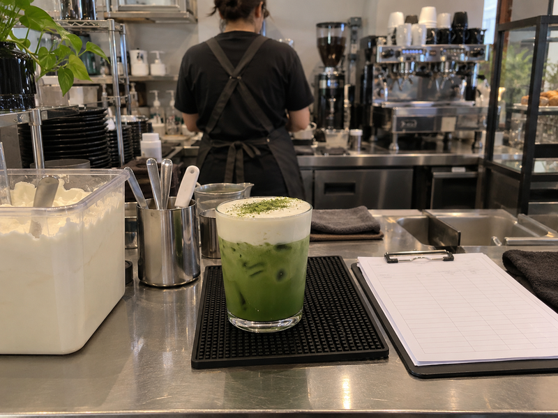 Completed cream-topped matcha at a working café counter