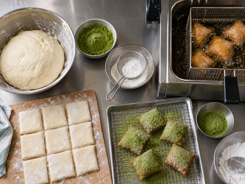 Fresh matcha beignets on a cafe tray